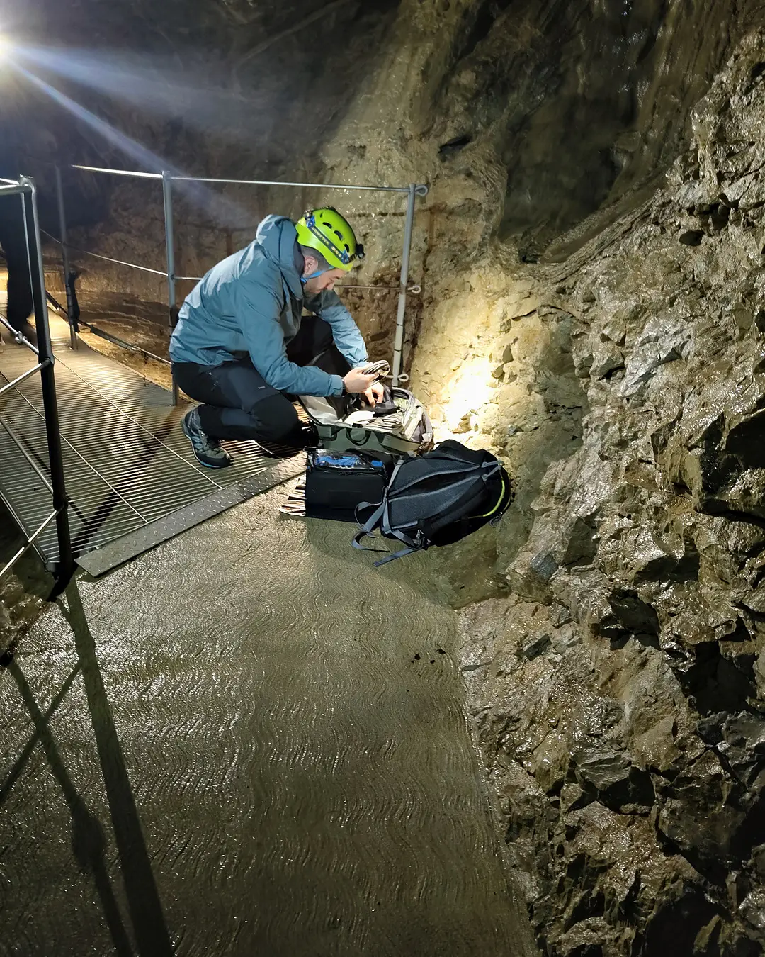 Andrea prepara l'attrezzatura su una passerella in grotta